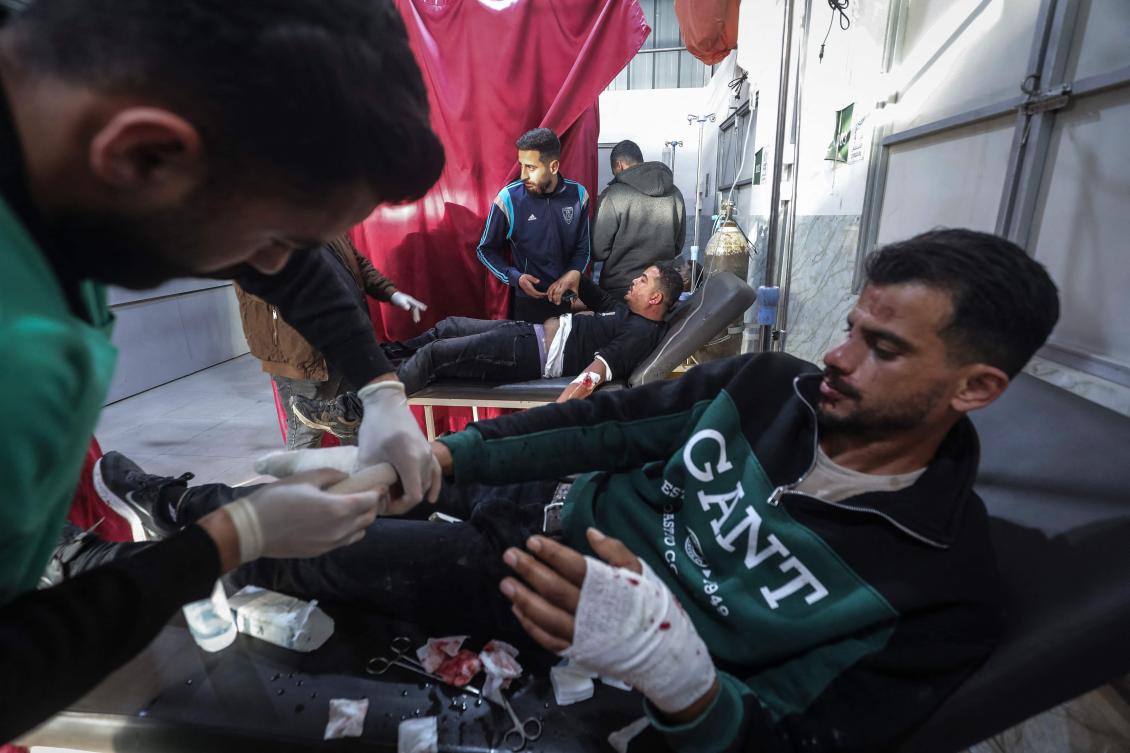 Injured men are treated for wounds sustained after a Palestinian police jeep that was targeted by an Israeli air strike in Nuseirat refugee camp in the central Gaza Strip on March 22, 2026. (AFP)