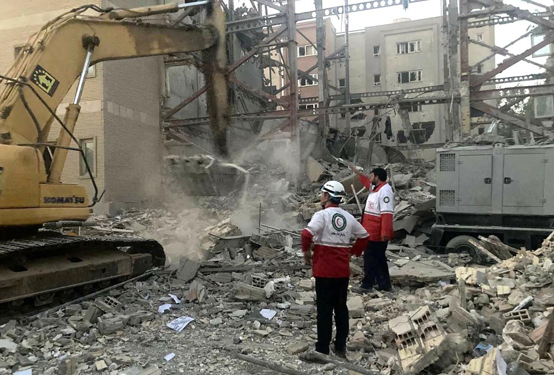 Above, Iranian Red Crescent members clear debris at a building destroyed during an earlier Israeli attack in Tehran. (Iranian Red Crescent/AFP file photo)