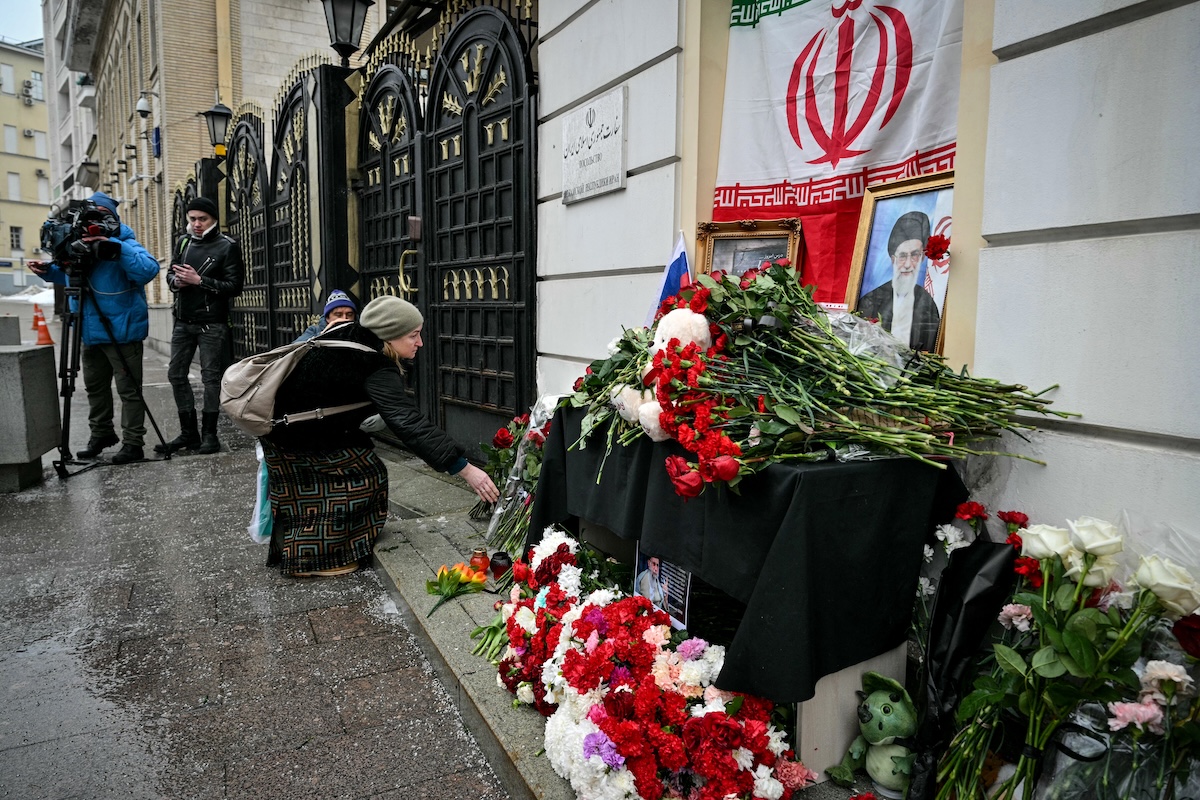 People lay flowers at a makeshift altar with a portrait of late Iran's supreme leader Ayatollah Ali Khamenei and a flag of the Islamic Republic of Iran outside the Iranian Embassy in Russia, in Moscow on March 2, 2026. (FILE/AFP)