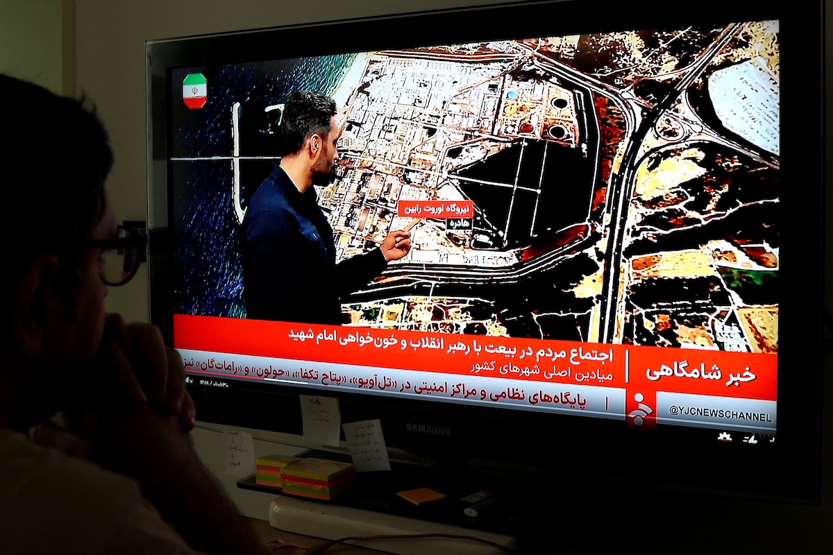 Above, an Iranian man watches the news on Iranian State TV in Tehran on March 23, 2026. (AFP)