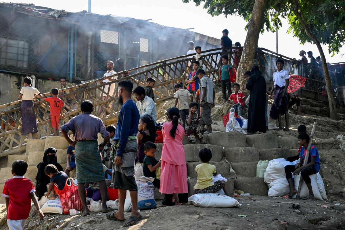Rohingya refugees waiting outside a distribution centre after collecting relief materials at the Kutupalong refugee camp in Cox's Bazar, Bangladesh. (AFP)