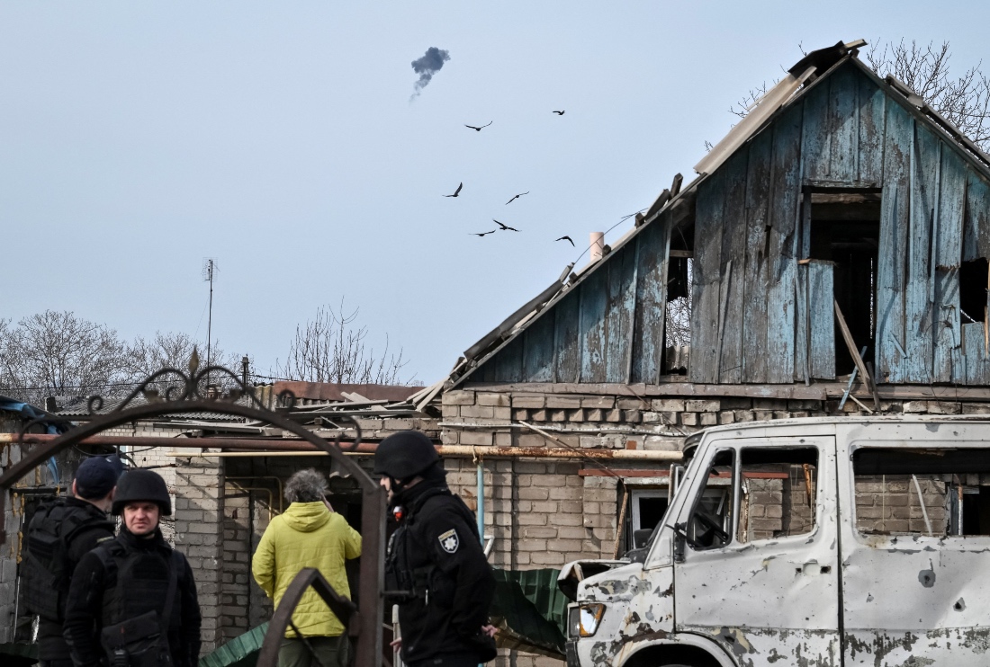 Ukrainian servicemen hit a Russian drone as police officers work at the site of a building hit by a Russian drone strike, in Zaporizhzhia, Ukraine. (Reuters)