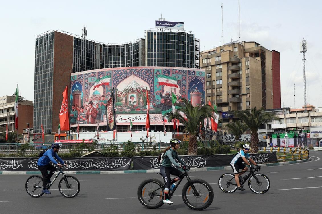 Cyclists ride past a giant billboard with a portrait of Iran's slain supreme leader Ayatollah Ali Khamenei (C) at the Valiasr Square in Tehran on March 22, 2026. (FILE/AFP)