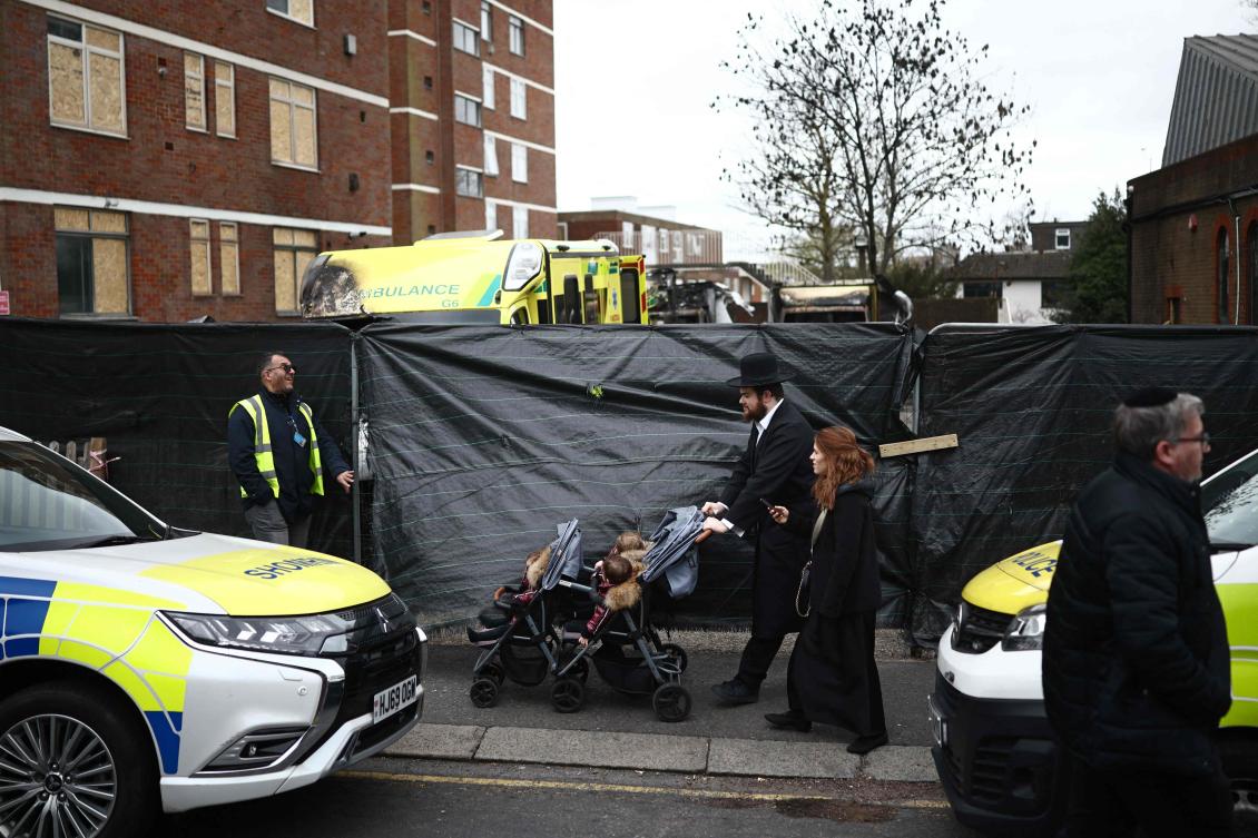 Members of the Jewish community pass the scene of an antisemitic arson attack in the Golders Green neighbourhood of north London, on March 24, 2026. (Photo by Henry NICHOLLS / AFP)