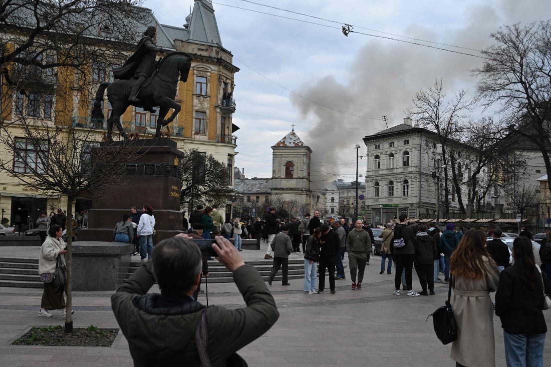 People look at smoke rising from a burning building following a Russian drone attack in Lviv, Ukraine. (AFP)