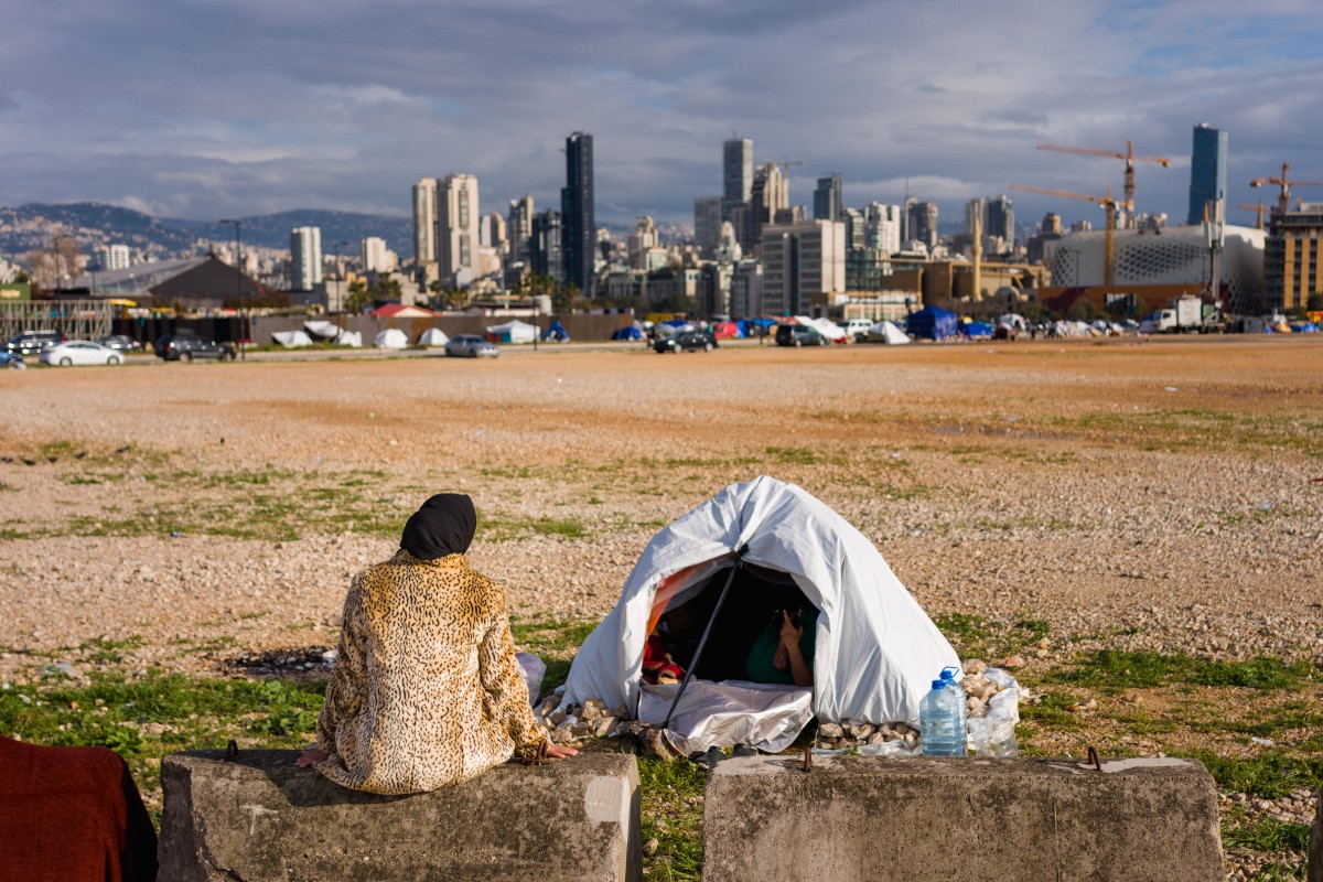 A displaced woman sits next to her tent in an unofficial camp, erected along Beirut’s seafront area, March 22, 2026. (AFP)