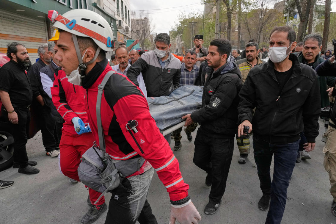 Iranian Red Crescent Society members on Friday carry away the body of a victim killed in a residential building that was hit by an overnight US-Israeli strike in Tehran. (AP)