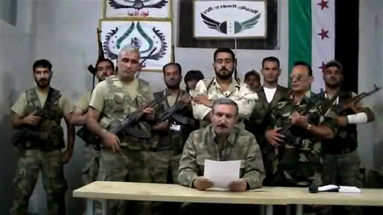 An image grab from a YouTube video uploaded on September 22, 2012, shows Free Syrian Army (FSA) chief Riad al-Asaad (C) reading a statement from an undisclosed location in Syria. (File / AFP)