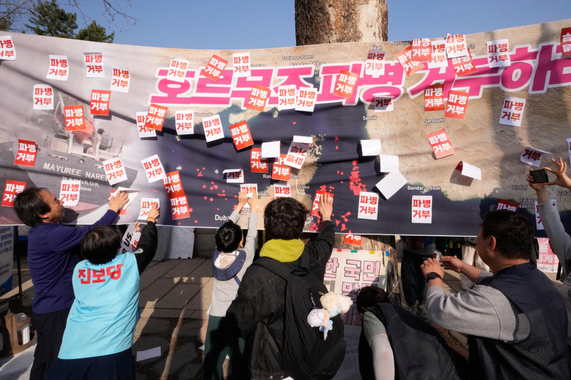 South Korean protesters attach stickers on a banner showing the Strait of Hormuz during a rally against the US and Israel attacks on Iran near the presidential office in Seoul, South Korea, Saturday, March 28, 2026. (AP)