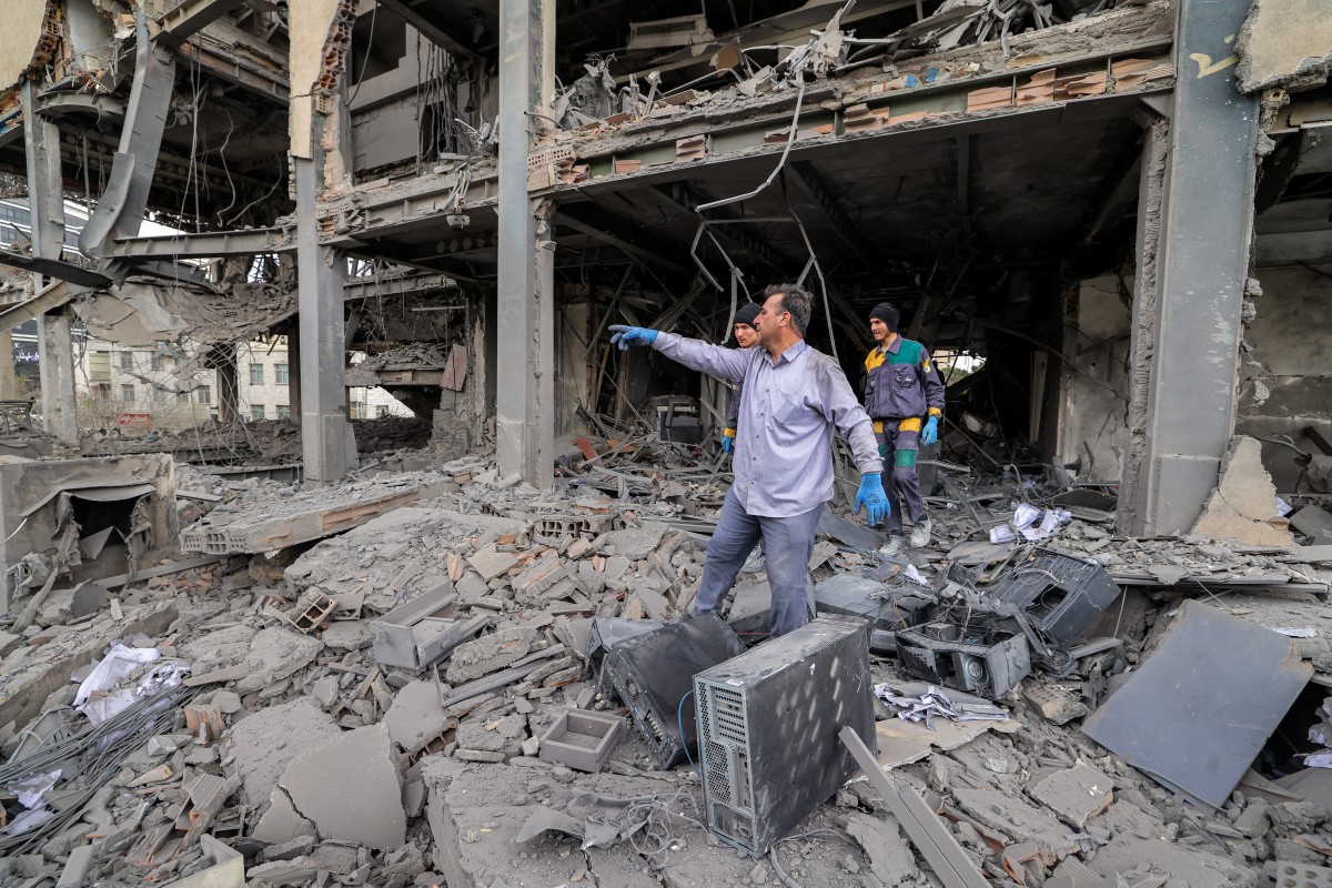 People retrieve computer servers and equipment from an office building that housed the offices of the Doha-headquartered news network Al-Araby TV following a missile strike in Tehran, March 29, 2026. (AFP)