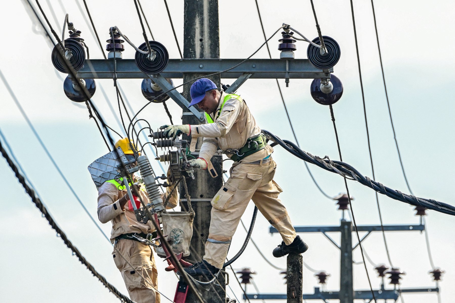 Lanka Electricity Company (LECO) workers carry out maintenance work on an electric pole in Colombo, Sri Lanka in 2025. (AFP)