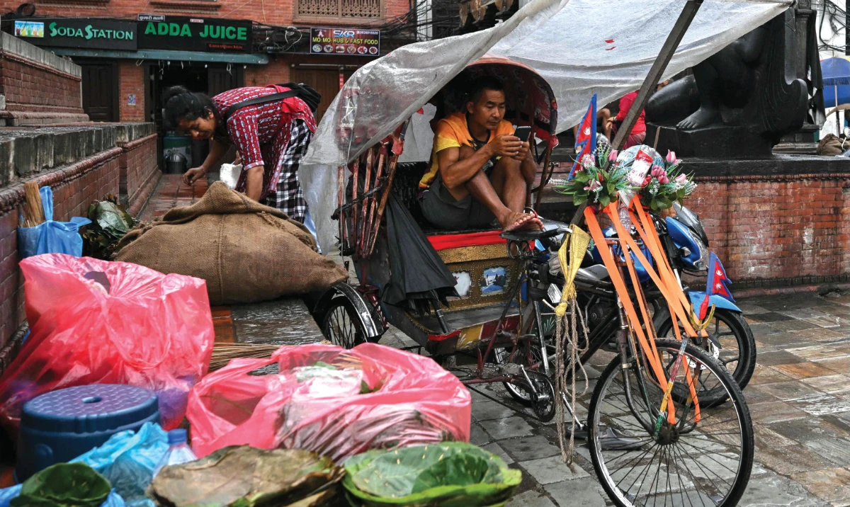 A rickshaw puller uses a mobile phone at the Durbar Square in Kathmandu on Sept. 13, 2025. (AFP/File)