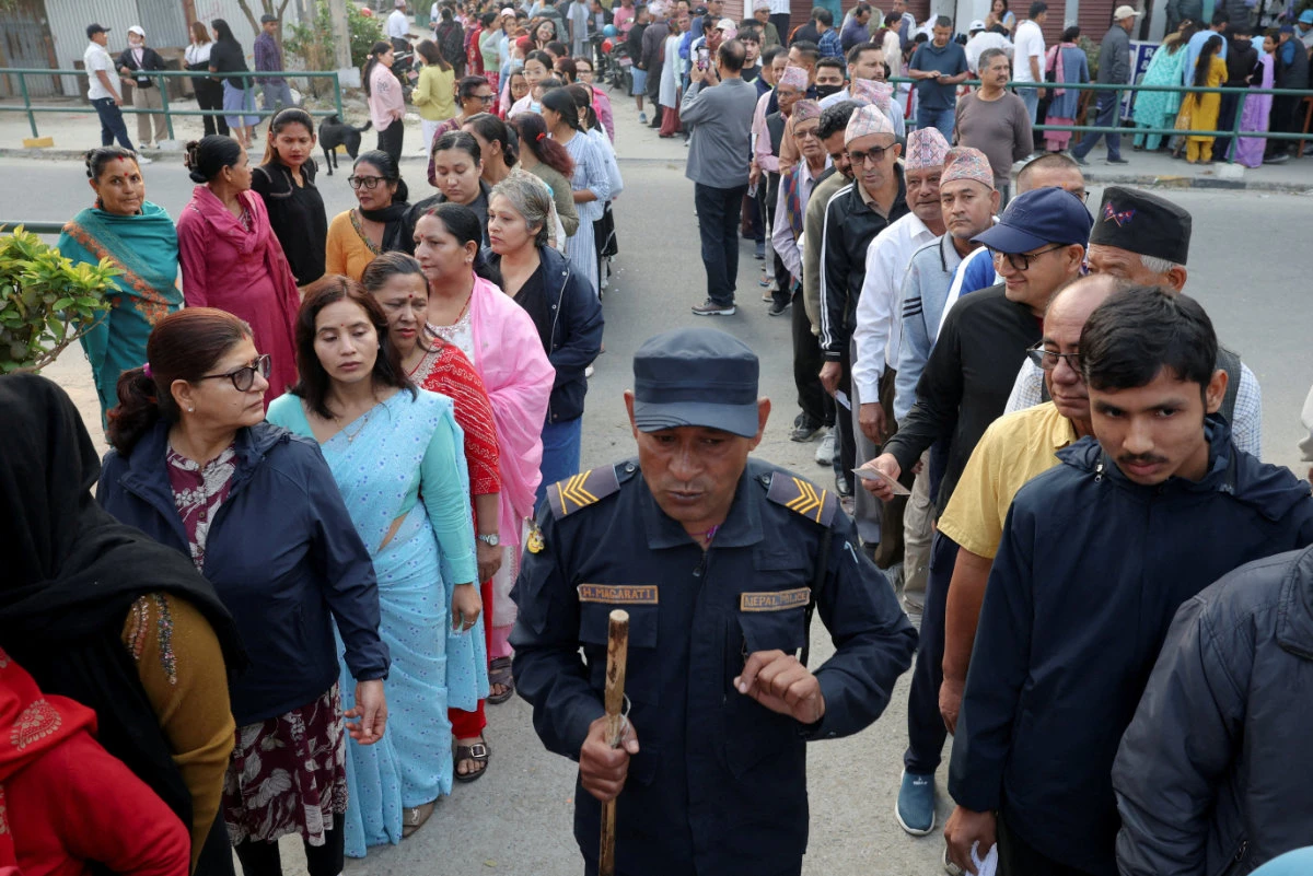 People stand in queues to vote outside a polling station, as a policeman walks by during the general election in Damak, Jhapa district, Nepal, on March 5, 2026. (REUTERS)