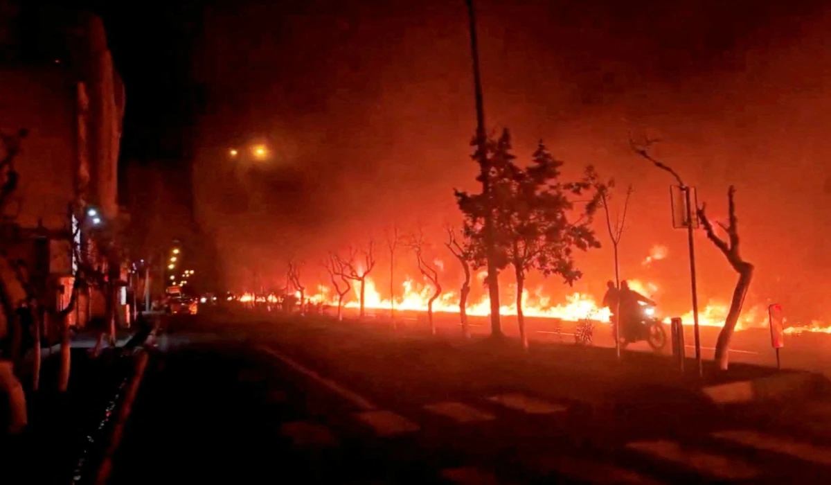 A motorcycle passes by fire burning along Tehran's Koohsar Boulevard, Iran, in this screengrab from video obtained from social media and released on March 8, 2026, amid the U.S.-Israeli conflict with Iran. (REUTERS)