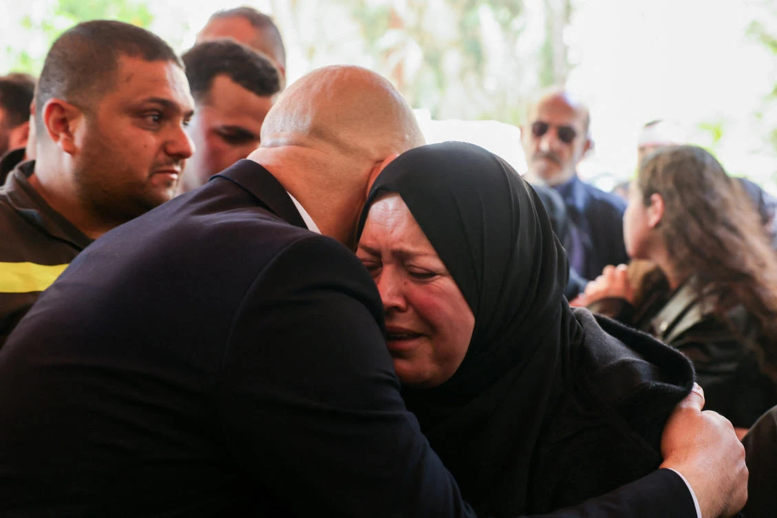 The wife of Fahmi Mahieddine Al-Chami, a member of the Lebanese Civil Defense who was killed on Wednesday in an Israeli airstrike targeting a vehicle in Sidon, is embraced during his funeral on Thursday. (Reuters)