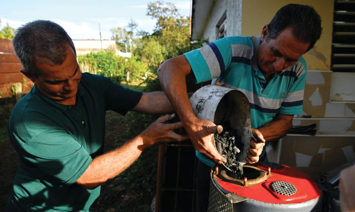 Carlos Pino and his nephew put charcoal into a welded fuel tank to fuel Pino’s modified car. (Reuters)