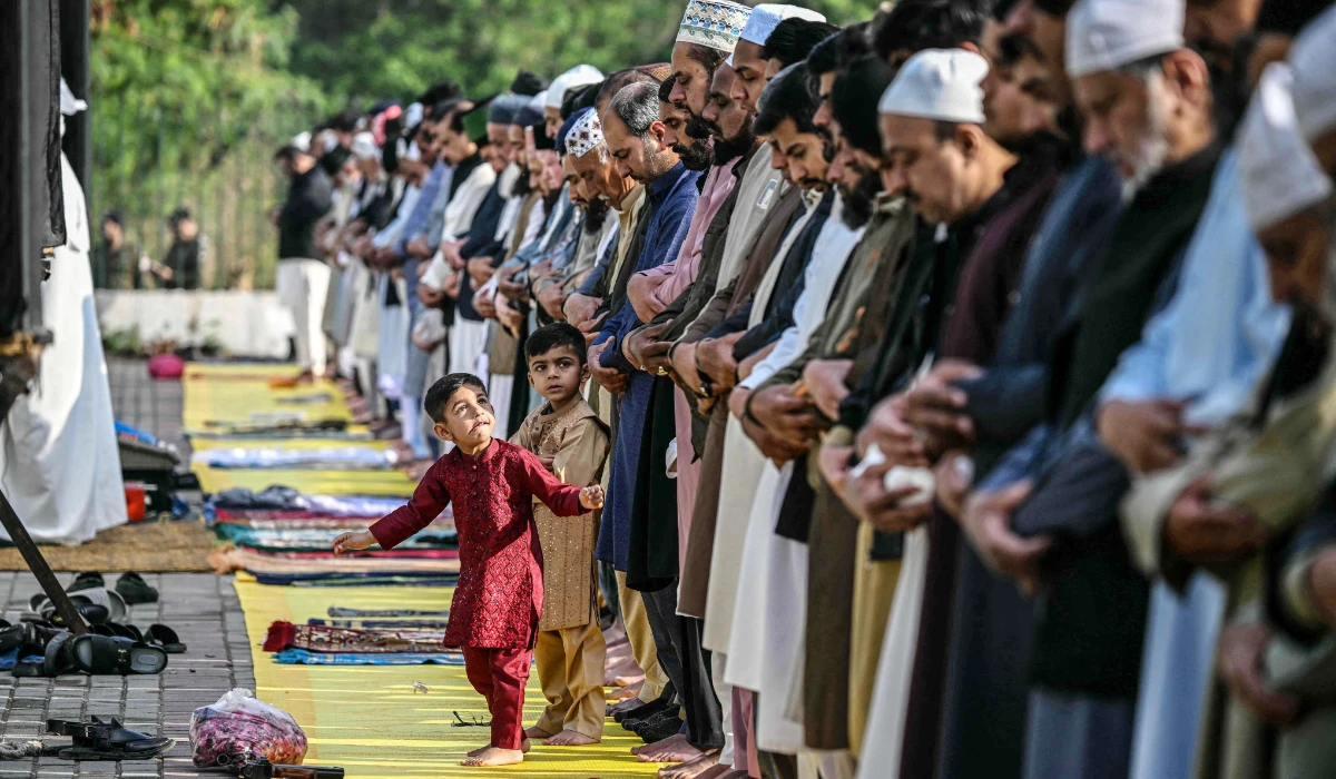 Children look at Muslim devotees offering Eid al-Fitr prayers, which marks the end of the Islamic holy fasting month of Ramadan, in Rawalpindi on March 21, 2026. (AFP)