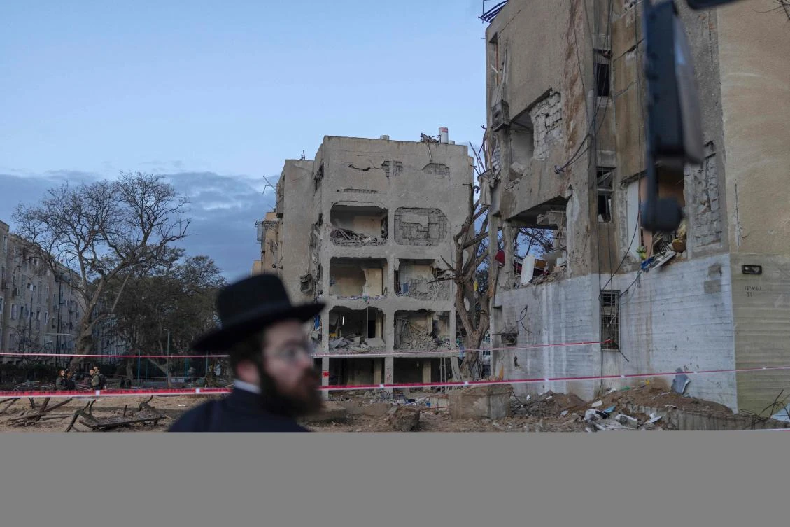 An Israeli Orthodox Jew inspects the site of an Iranian missile strike in Arad on March 22, 2026. (AFP)