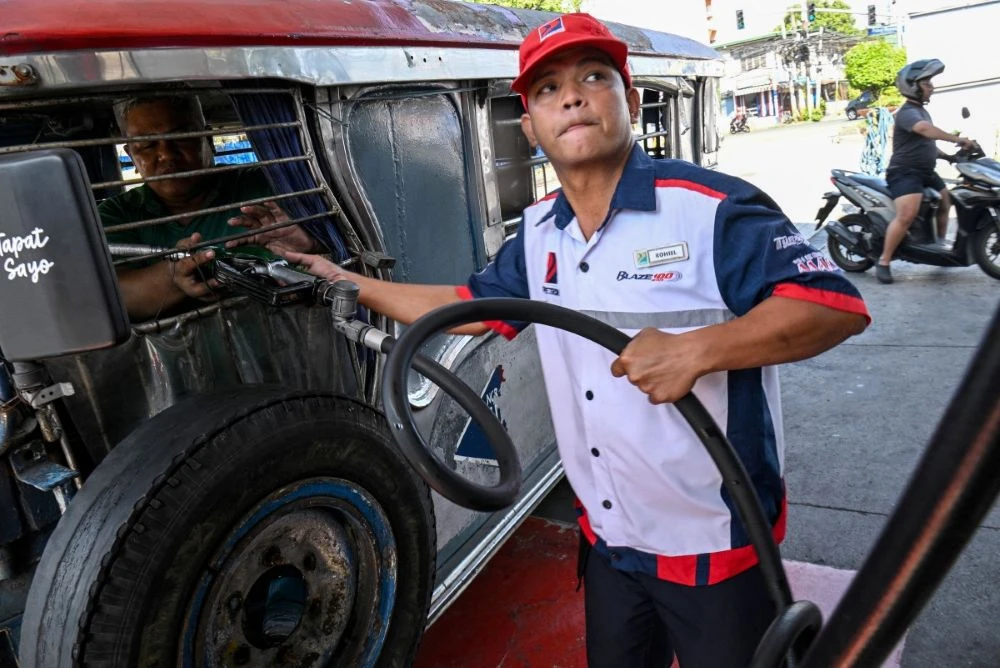 Jeepney driver Eric Helera refuels his vehicle with diesel at a fuel station in Manila on March 23, 2026. (AFP)