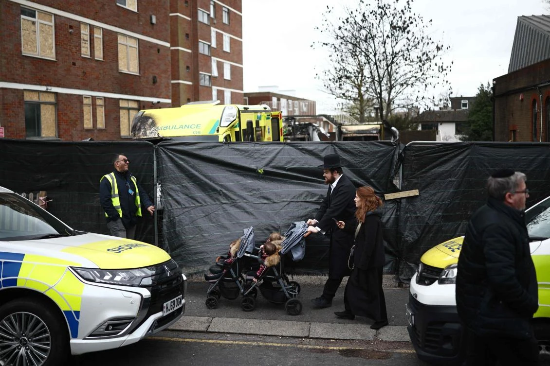 Members of the Jewish community pass the scene of an antisemitic arson attack in the Golders Green neighbourhood of north London, on March 24, 2026. (Photo by Henry NICHOLLS / AFP)