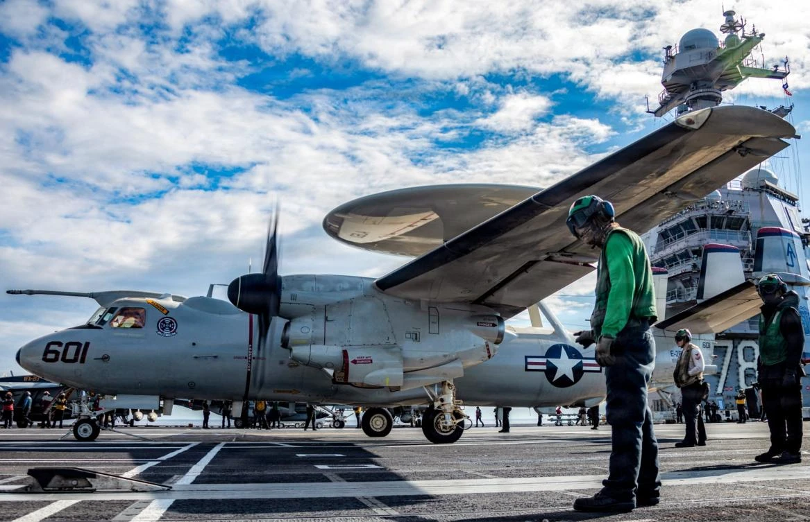 Above, US Sailors observes as an E-2D Hawkeye aircraft approaches an aircraft catapult to launch from the flight deck of USS Gerald R. Ford on March 1, 2026. (US Navy/AFP)