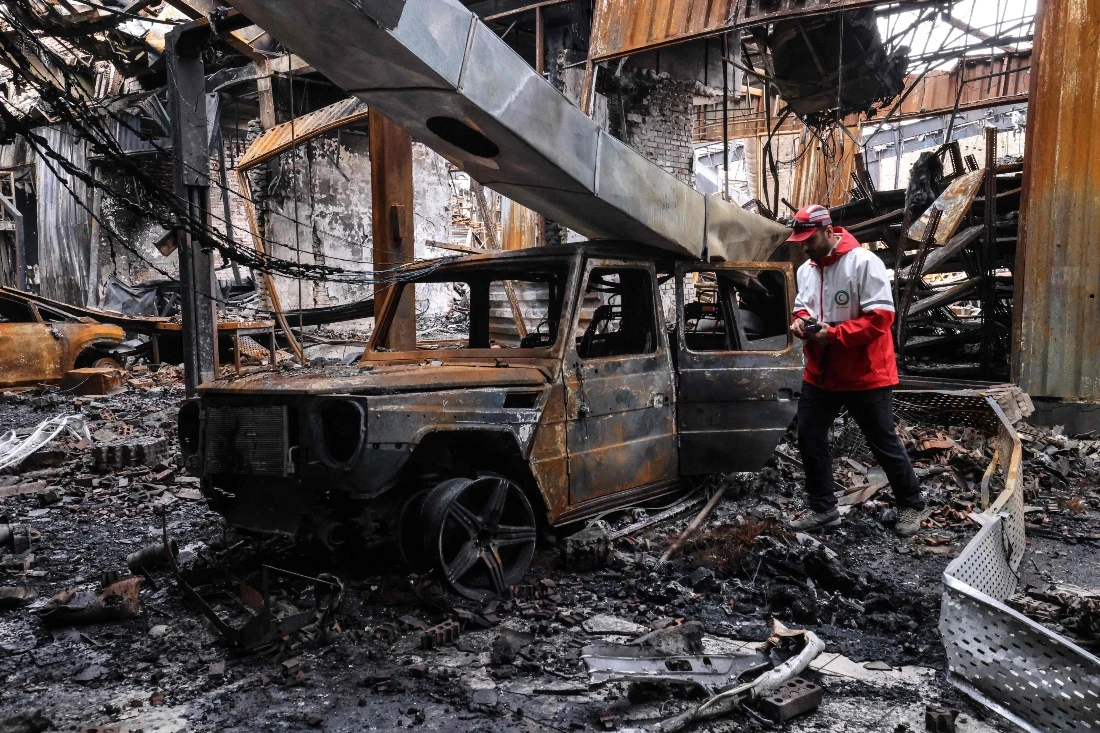 A member of the Iranian Red Crescent walks past the wreckage of a vehicle at car service centre in eastern Tehran, Iran. (AFP)