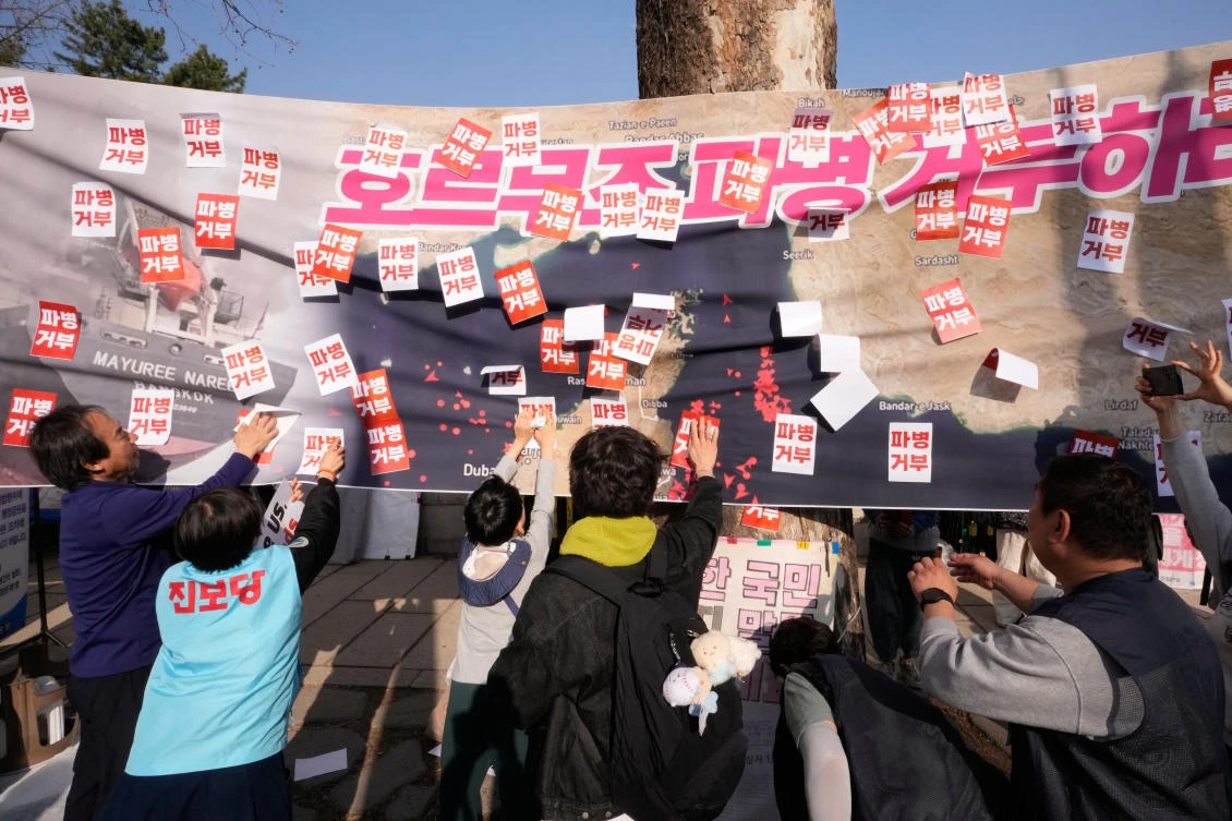 South Korean protesters attach stickers on a banner showing the Strait of Hormuz during a rally against the US and Israel attacks on Iran near the presidential office in Seoul, South Korea, Saturday, March 28, 2026. (AP)