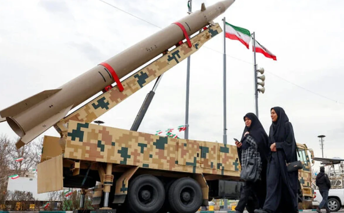 Women walk past a ballistic missile launch vehicle in Tehran on February 11. (AFP/File Photo)