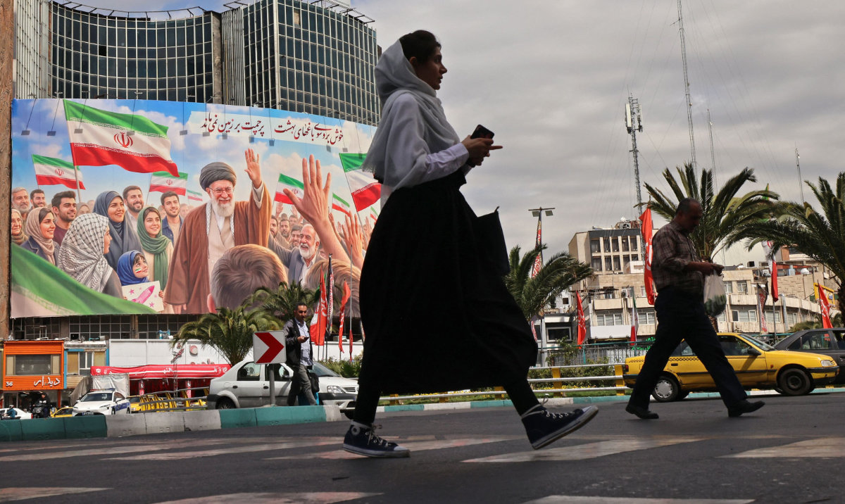 Commuters make their way past a giant billboard of slain Iranian supreme leader Ayatollah Ali Khamenei in Tehran. (AFP)