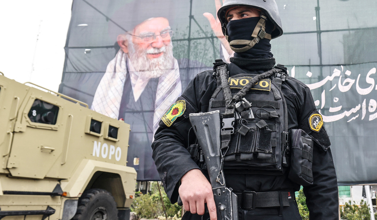 A member of the Iranian security forces stands guard next to a banner honouring Iranís slain supreme leader Ayatollah Ali Khamenei in Tehran on March 31, 2026. (AFP)