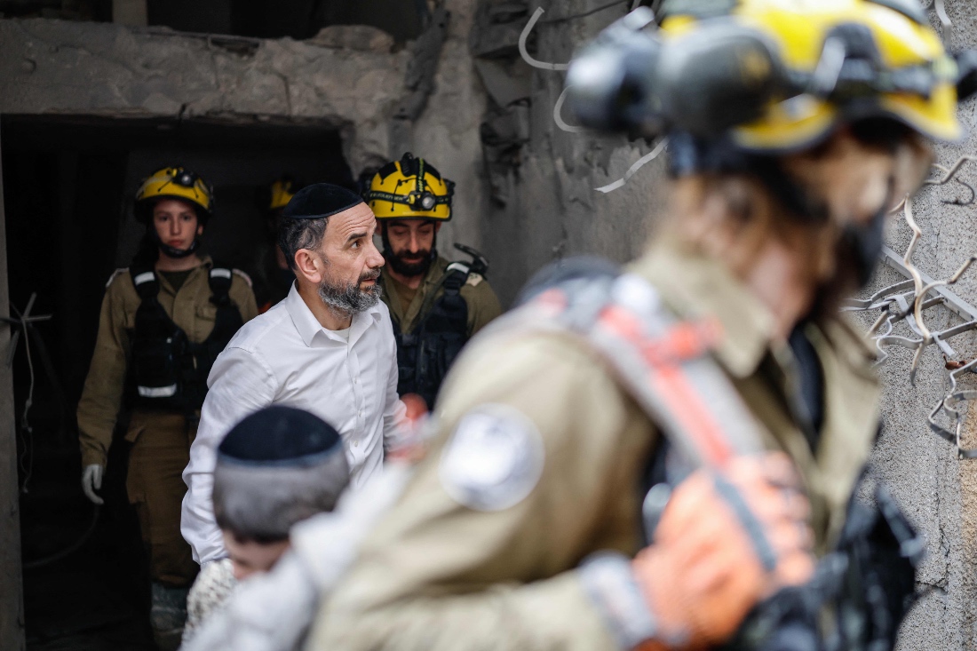 A man walking alongside first responders surveys the damage at the scene of an impact following an Iranian strike over Bnei Brak in central Israel. (AFP)