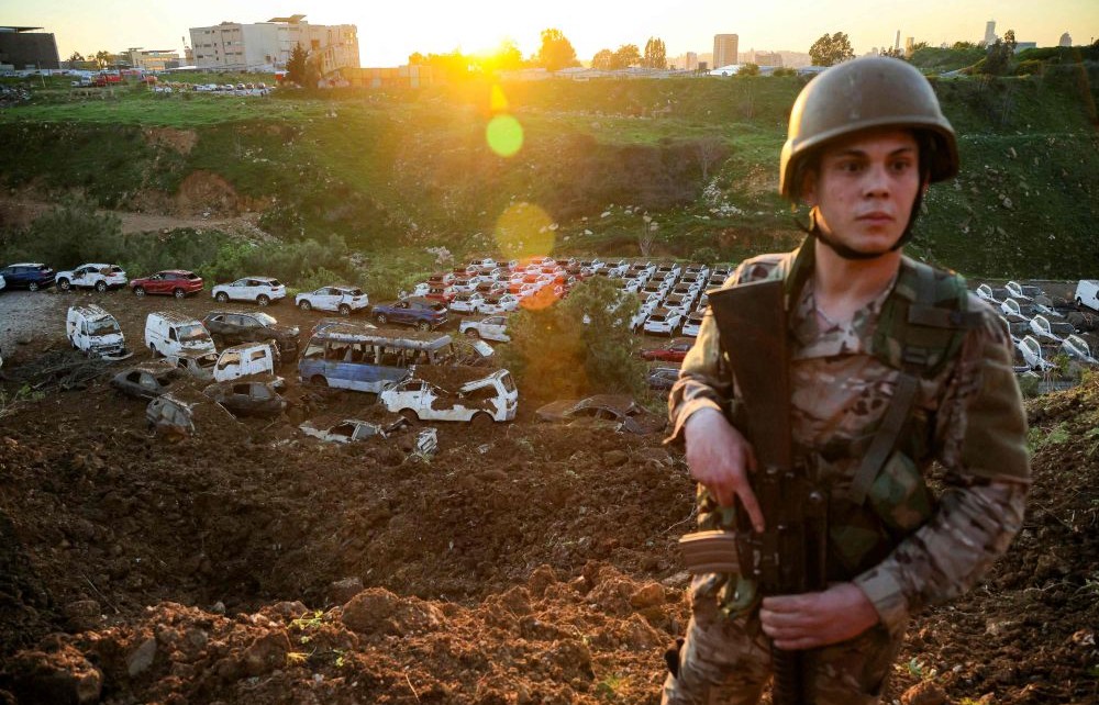 A Lebanese Army soldier stands guard before damaged and destroyed vehicles at a parking lot in Dekwaneh, on the eastern outskirts of Beirut, on March 31, 2026. (AFP)