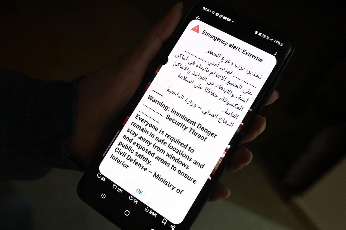 Above, a phone displays an alert message as sirens sound during an Iranian missile or drone attack in Kuwait City early on March 31, 2026. (AFP)