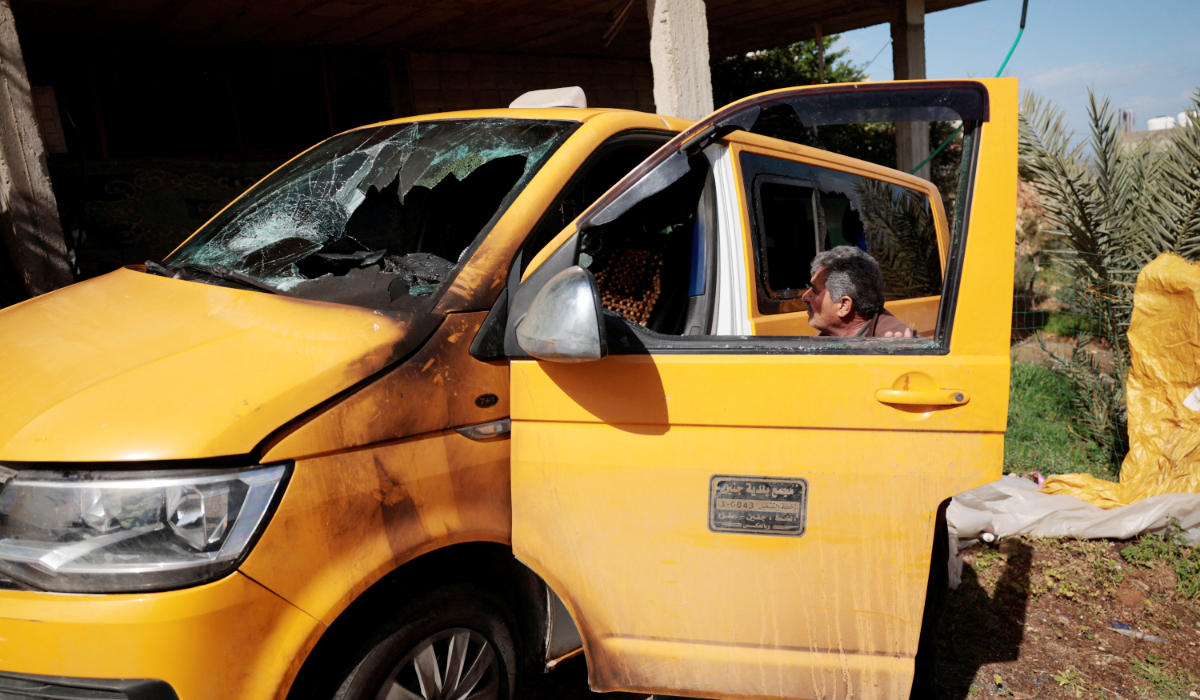 A man looks at a damaged vehicle, which Palestinians say was burned by Israeli settlers last night, in Al-Fandaqumiya, near Jenin, in the Israeli-occupied West Bank, March 22, 2026. (REUTERS)