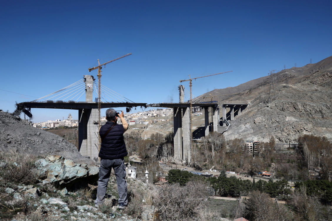 A man stands near the B1 bridge damaged by a strike, as the US-Israeli conflict with Iran continues, in Karaj, Iran, April 3, 2026. (WANA via REUTERS)