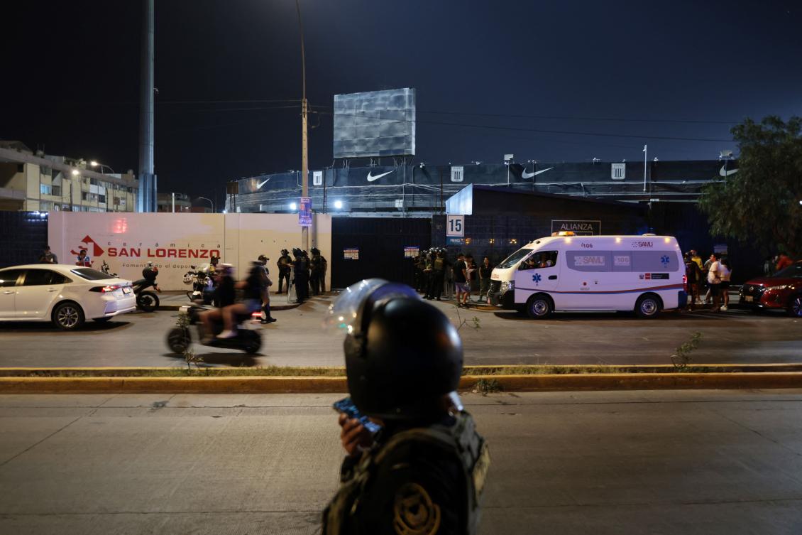 Police officers stand guard at the entrance of the Alejandro Villanueva Stadium while relatives wait for news after an accident in the stands where Alianza Lima's fans were cheering for their team on the eve of the match against Universitario in Lima on April 3, 2026. (AFP)