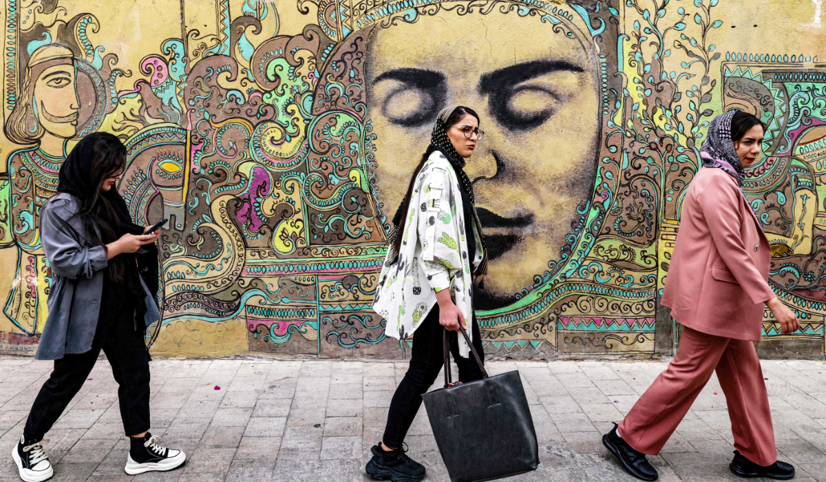 Women walk past a mural painting by an Iranian artist displayed on a wall in the central Iranian city. (AFP file photo)