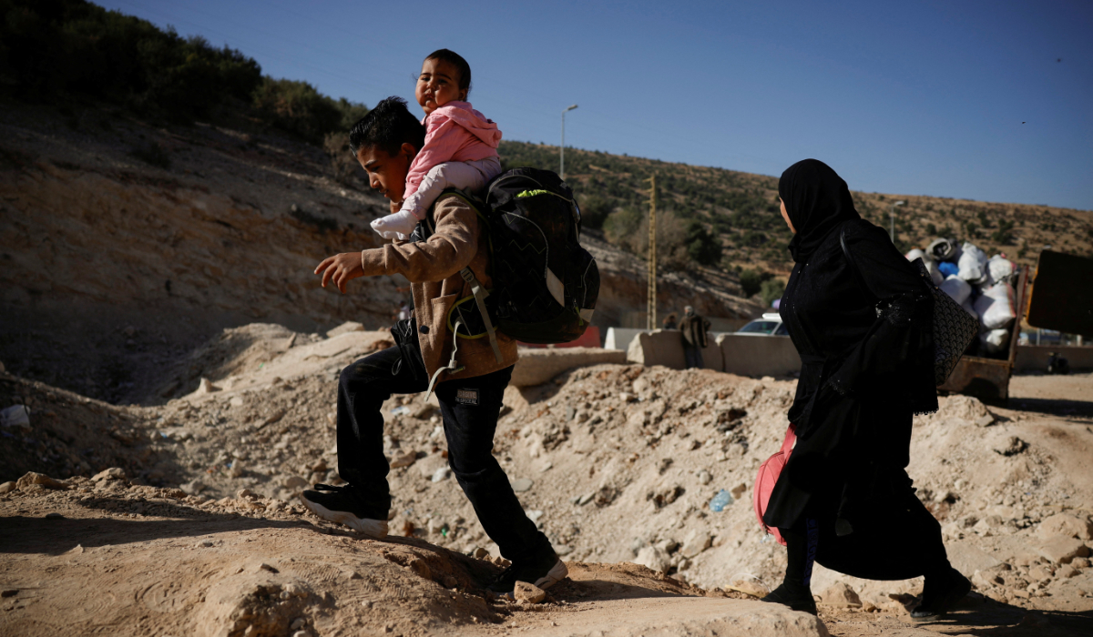 A boy carries a child while crossing from Lebanon into Syria on foot at the Masnaa border crossing on Oct. 14, 2024. (Reuters file photo)