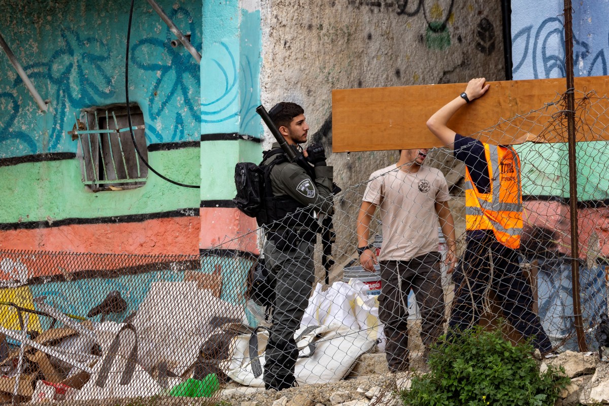 An israeli soldier look on as Israeli authority employees empty a Palestinian home as 11 Palestinian families in the Batan al-Hawa area of Silwan. (AFP)