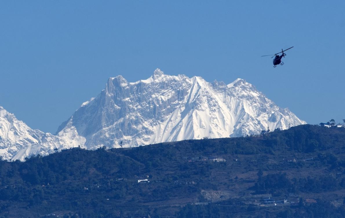 Above, a helicopter flies with rescue team in front of the Annapurna mountain range, in Pokhara, west of Kathmandu on Jan. 22, 2020. (AFP file photo)