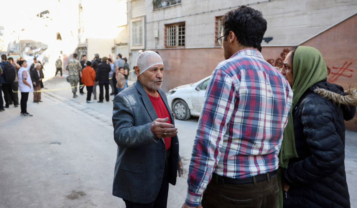 An injured resident speaks to people at the site of Israeli-American strikes that according to local media reports destroyed the Rafi-Nia Synagogue and nearby residential buildings in Tehran, on April 7 2026. (AFP)