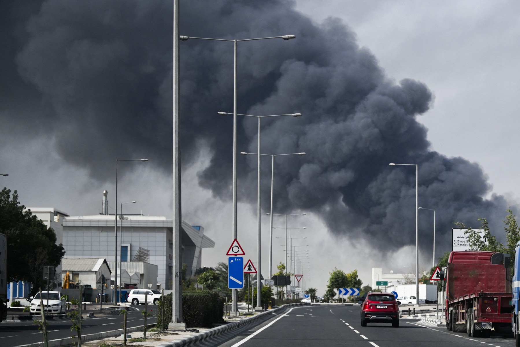 Motorists drive past a plume of smoke rising from a reported Iranian strike in Doha’s industrial district. (File / AFP)
