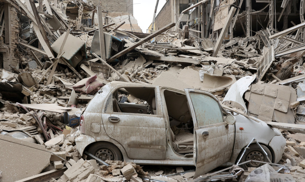 A destroyed vehicle amid rubble at the site of a US-Israeli strike on a residential building in a Tehran neighborhood. (Reuters)