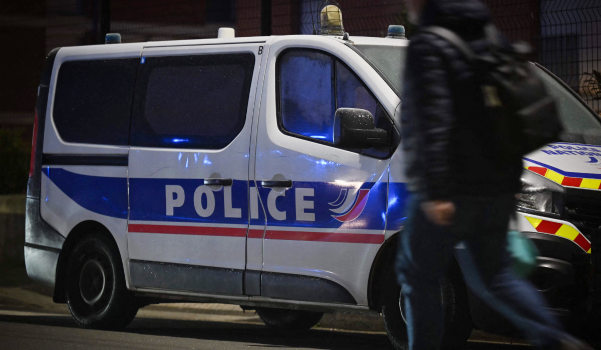A pedestrian walks past a police vehicle parked along a street in Le Havre. (AFP file photo)