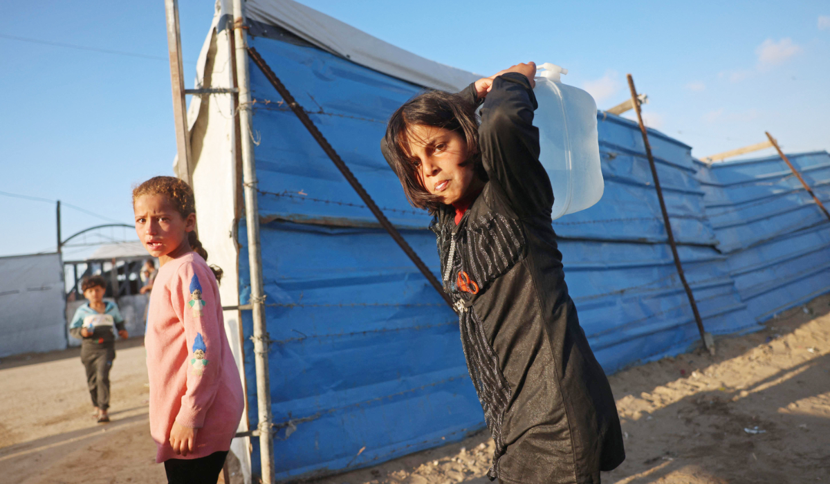 A girl carries a water container at a makeshift camp in Khan Younis. (AFP)