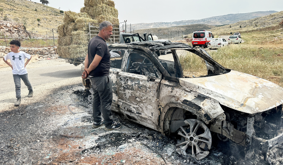 Palestinians check a car burned by Israeli settlers during clashes near Ramallah in the Israeli-occupied West Bank May 26, 2023. (REUTERS)