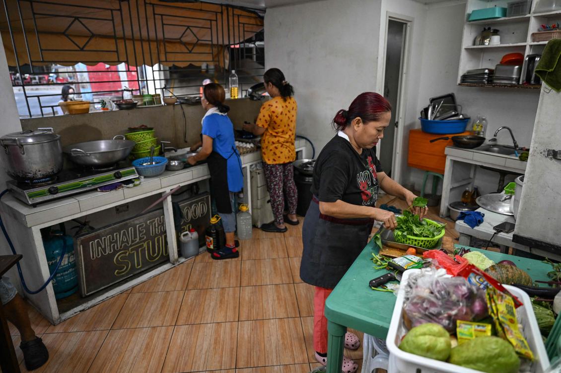 Women cook at a curbside canteen in Manila on April 7, 2026. The rising price of LPG has hit the import-dependent archipelago's humble street food vendors hard. (AFP)