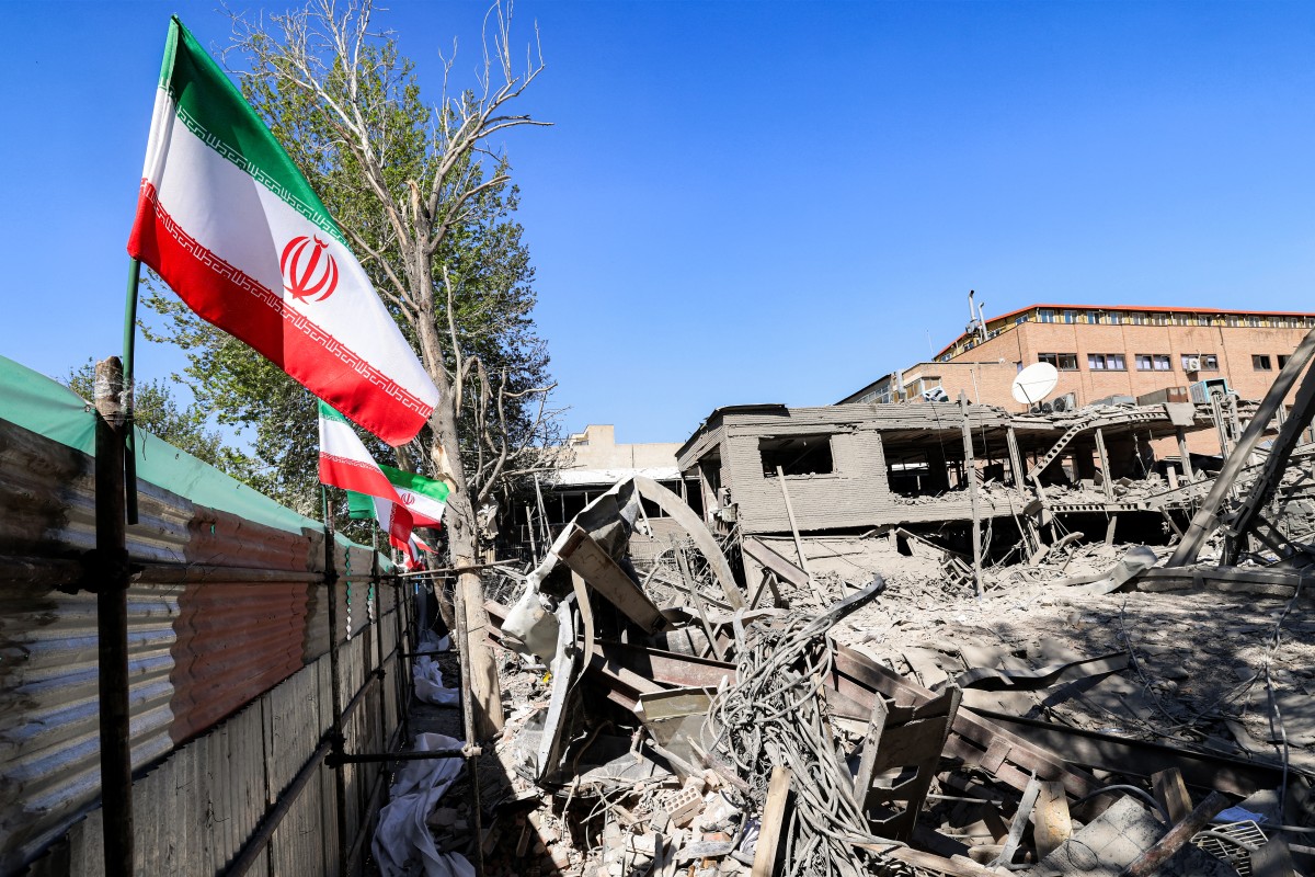 An Iranian national flag is placed by the rubble of a collapsed building following strikes at Sharif University of Technology in Tehran, Iran. (AFP)