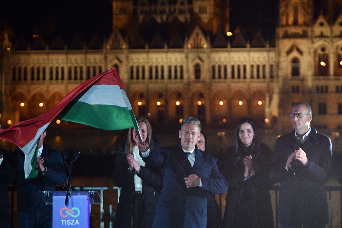 Peter Magyar, leader of the pro-European conservative TISZA party, waves the national flag during celebrations at the election night party on the banks of the Danube river with the Parliament building in the background, in Budapest, Hungary. (AFP)
