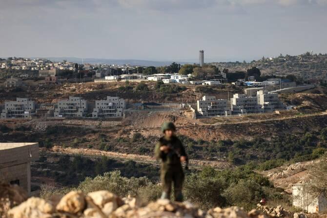 A member of the Israeli security forces stands guard, overlooking the Nahliel settlement (in the background), as security forces block Palestinians reaching their land to harvest olives, in the village of Kobar, near Ramallah, in the Israeli-occupied West Bank on October 18, 2025. (File/AFP)